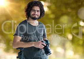 happy photographer with camera on hands and blurred forest with lights and flares behind