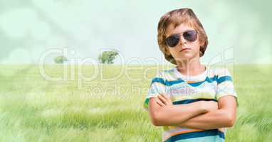 Boy with sunglasses arms folded against meadow