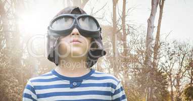 Boy with goggles against blurry trees with flare