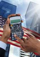 Hand holding a calculator  against american flag and skyscraper