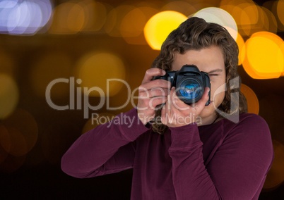 young hipster photographer taking a photo in the city at nights ( blurred lights)