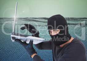 Hacker with hood using a laptop in front of digital number field