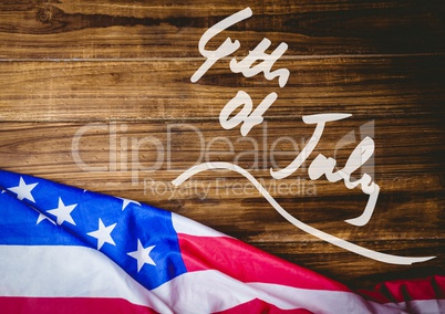 White fourth of July graphic against wood table and american flag