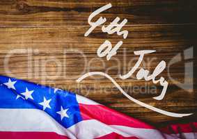 White fourth of July graphic against wood table and american flag