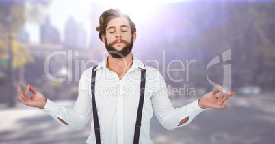 Millennial man meditating against blurry street with flares