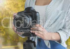 photographer hands with reflex (foregrund) in the park. Flares and lights