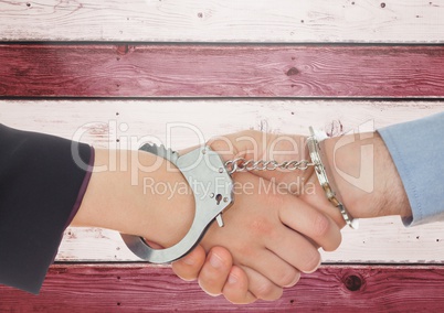 Two 3d people handshaking and tying bu handcuffs against wooden background