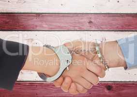 Two 3d people handshaking and tying bu handcuffs against wooden background