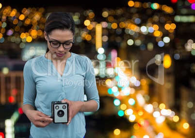 photographer taking a photo with vintage camera. Blurred city lights background
