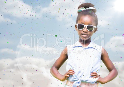 Girl in sunglasses hands on hips against sky with flare and confetti