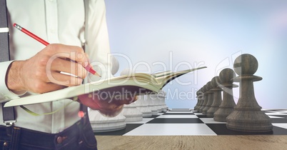 Man with notebook mid section against 3D chess pieces and purple abstract background