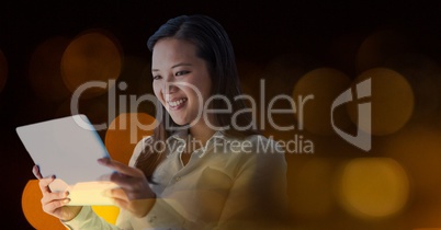 Smiling woman using a digital tablet in lights