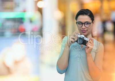photographer with glasses taking a photo with vintage camera. Blurred  store  lights on back.