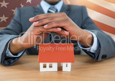 Business man covering a 3D house against american flag