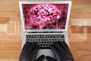 Hacker wearing gloves using a laptop  with a pink brain on desktop background