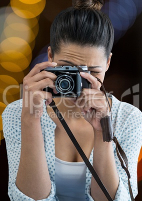 photographer with vintage camera taking a photo. Yellow and blue blurred lights behind