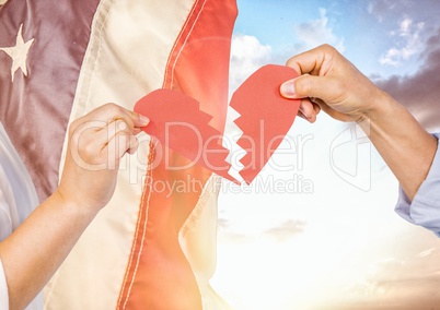 Hands holding a broken heart against 3d fluttering american flag