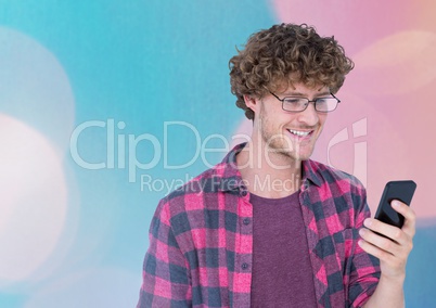 Smiling man texting against colored lights background