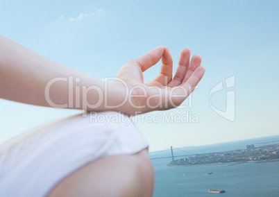 Hand and knee of meditating woman against coastline