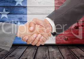 3d handshaking against a wooden background with american flag