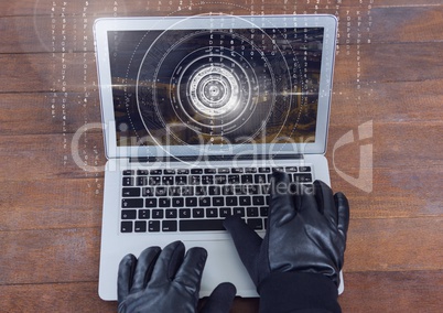 Gloved hands typing on a laptop on a wood table