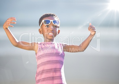 Boy in sunglasses hands out against blurry beach with flare