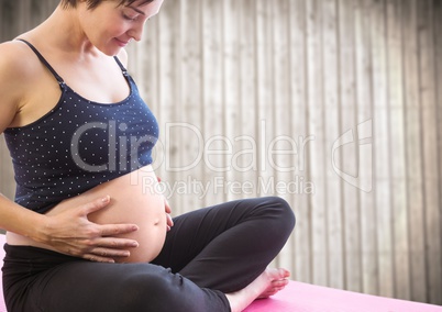 Pregnant woman meditating against blurry wood panel