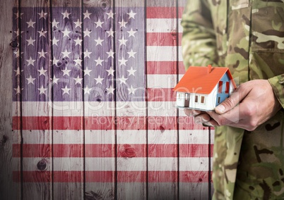 Close up of soldier holding a little house in front of american flag