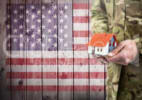 Close up of soldier holding a little house in front of american flag