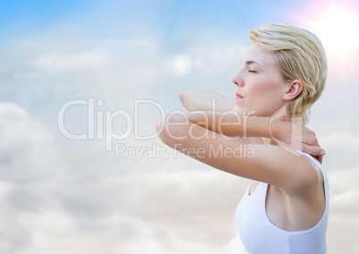 Woman stretching against sunny sky