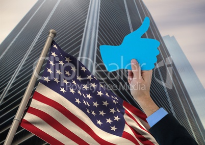 Part of man holding a 3D thumb up against american flag and skyscraper