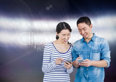 Smiling couple texting against shiny background