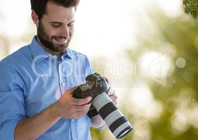 photographer looking the images on the camera. Green and white blurred lights and flares background