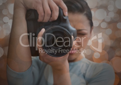 photographer foreground taking a photo with reflex. Blurred  brown lights background and overlap