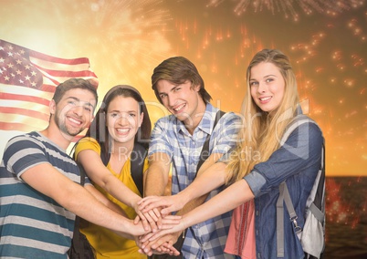 Friends with hands together against american flag and fireworks