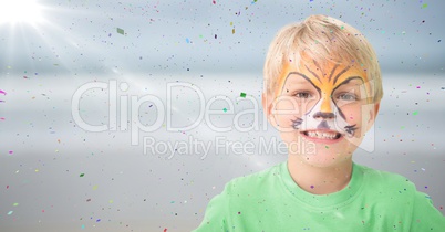 Boy with tiger face paint against blurry beach with flare and confetti