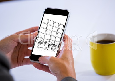 hands with phone with coffee behind. On the screen of the phone a blueprint of the design of the new