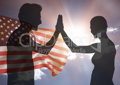 Shadow of people high fiving against american flag and sun