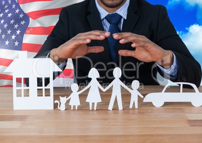 Business man showing 3D family, car and house on paper against american flag