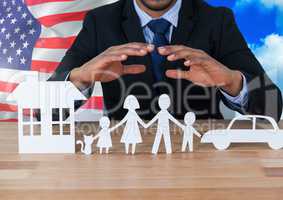 Business man showing 3D family, car and house on paper against american flag