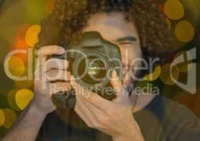 young photographer taking a photo ( foreground) with green and yellow bokeh background and overlap