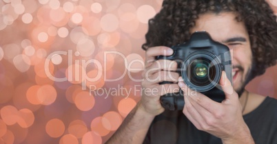 happy young photographer taking a photo (foreground) . Orange and white bokeh