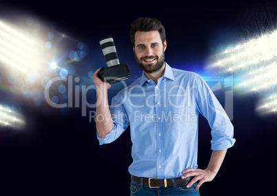 photographer with camera on hand and stadium lights behind
