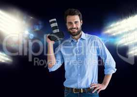 photographer with camera on hand and stadium lights behind