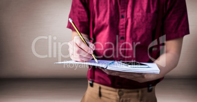 College student mid section with notebook against pink wall