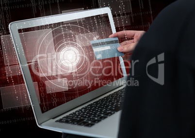 Close up of 3D hacker's hand using a laptop while holding a credit card