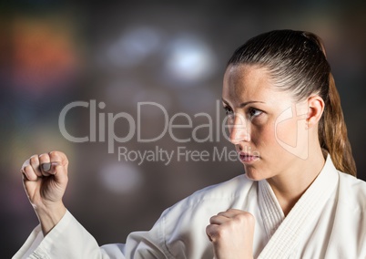 Woman in karate suit posing against blurry brown background