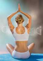 Back of woman meditating against blurry blue and brown background