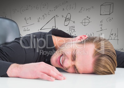 Frustrated business man on desk against grey background and math graphics