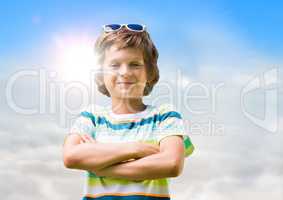 Boy in sunglasses arms folded against sky and sun with flare